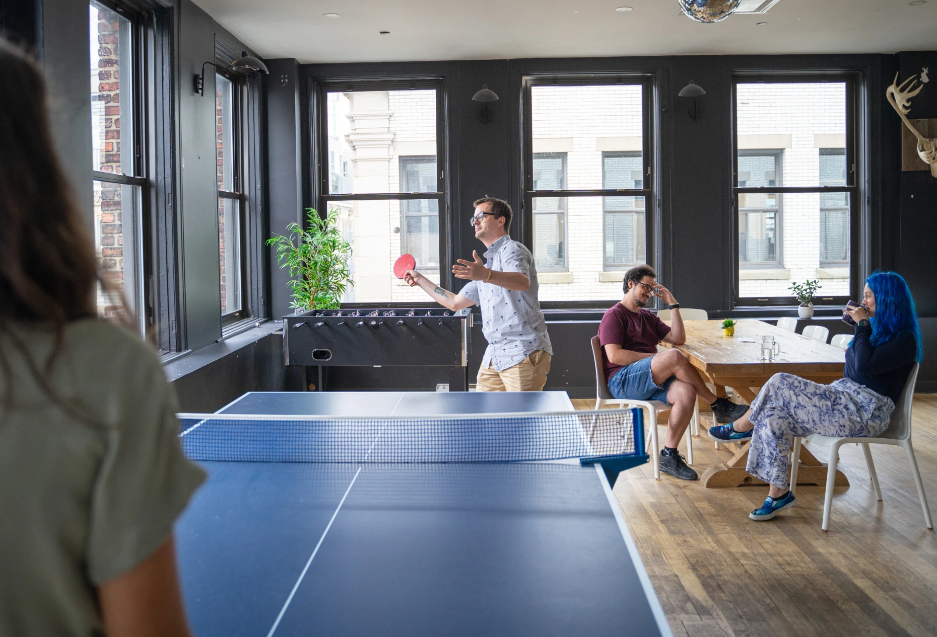 Colleagues enjoying a break while chatting or playing ping pong.